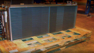 A large coil unit resting on a heavy-duty wooden pallet designed as custom packaging for HVAC components.