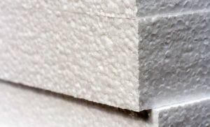 Close-up view of stacked white foam sheets used as protective industrial packaging, showcasing the textured surface and lightweight, cushioning material ideal for safeguarding products during shipping and handling.